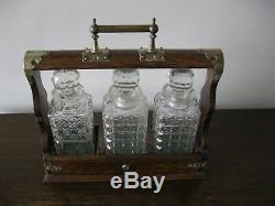 An antique Victorian oak three cut glass decanters tantalus with s/p mounts
