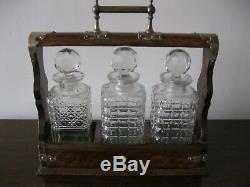 An antique Victorian oak three cut glass decanters tantalus with s/p mounts